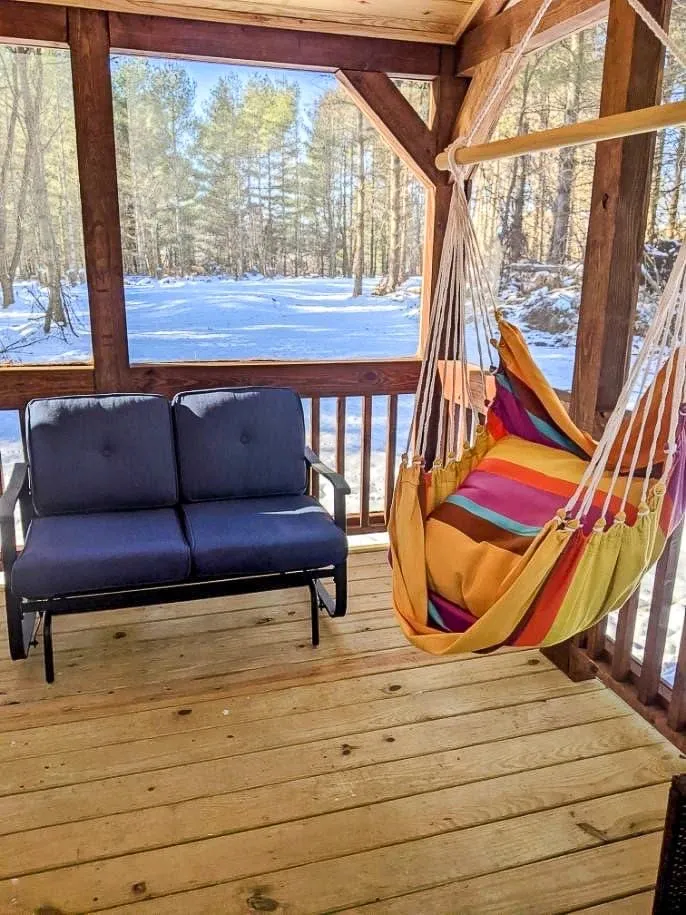 ark Model RV porch with chairs overlooking snowy woods, creating a serene and private cabin retreat in Brevard.